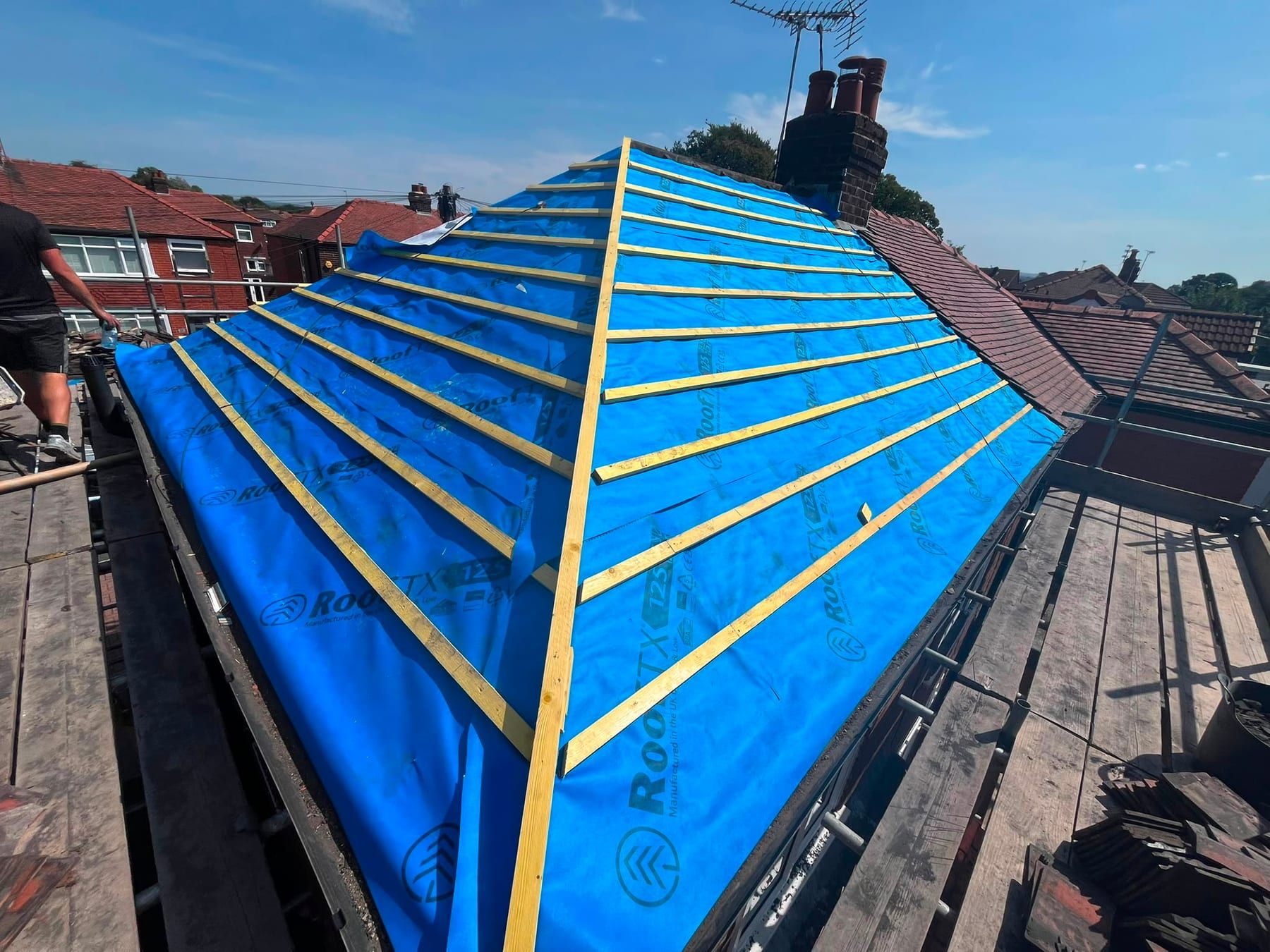 A stripped hip roof covered in blue breathable membrane with new timber battens fixed across it